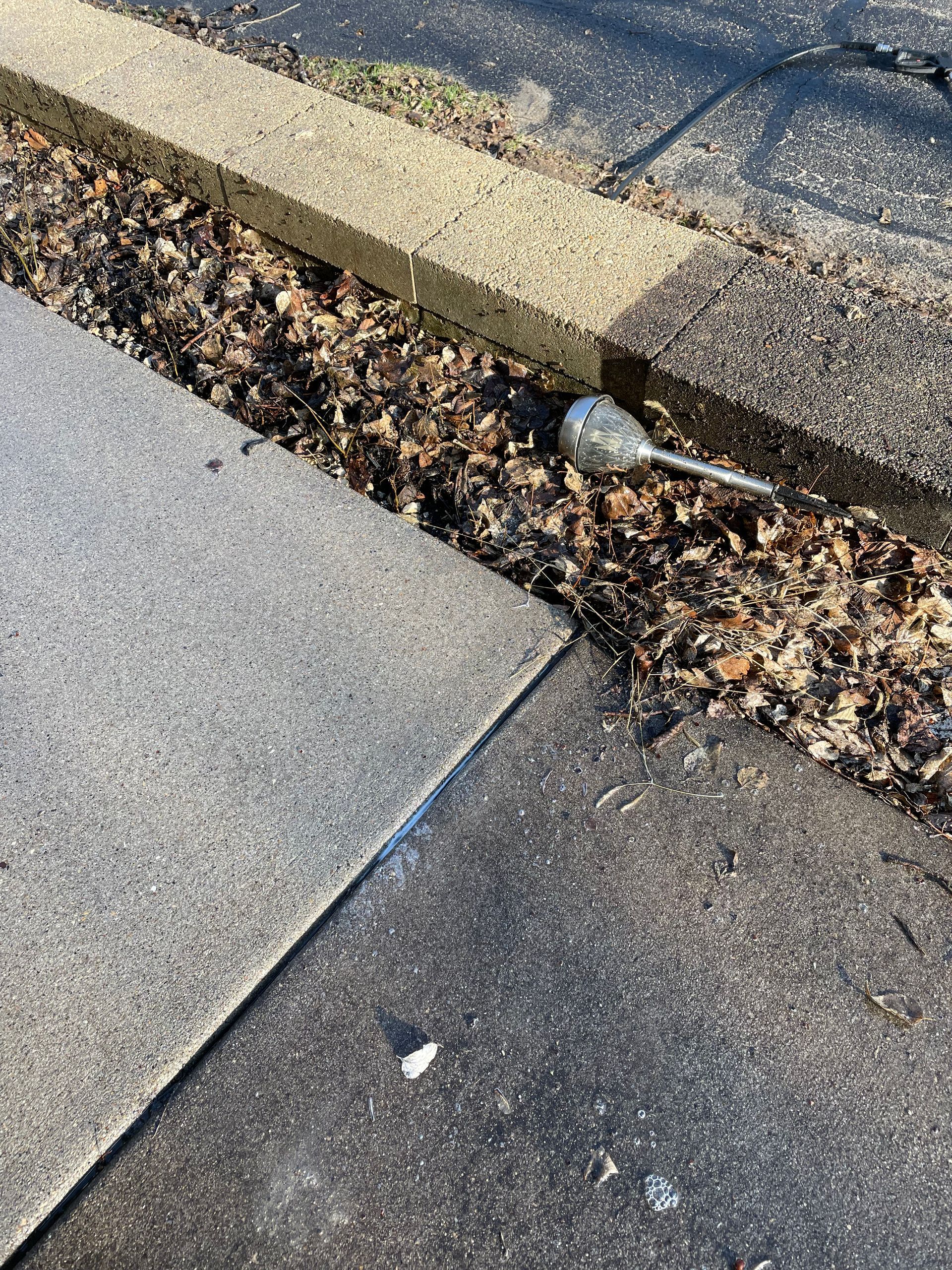 A spoon is laying on the sidewalk next to a curb.
