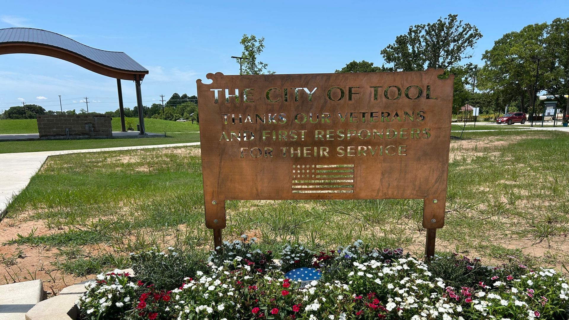 A sign for the city of tool is surrounded by flowers