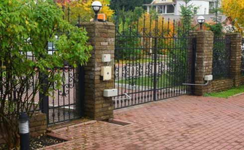 A Brick Fence With A Metal Gate And A Brick Driveway Leading To A House – Mishawaka IN - Milestone Fence