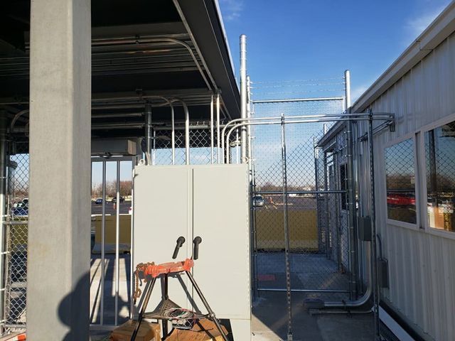 A Chain Link Fence Surrounds A Building With A Ladder In Front Of It – Mishawaka IN - Milestone Fence