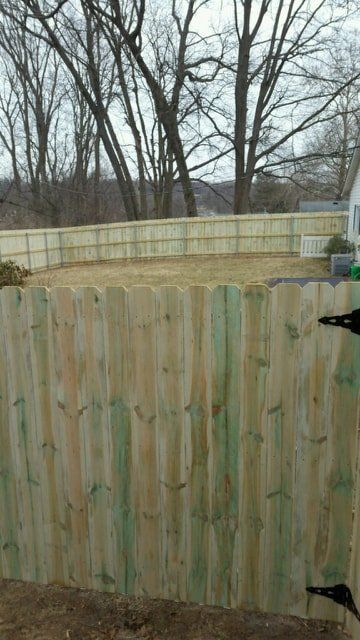 A Wooden Fence Surrounds A Yard With Trees In The Background – Mishawaka IN - Milestone Fence