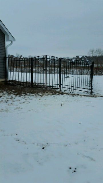 A Black Fence Is Surrounded By Snow In Front Of A House – Mishawaka IN - Milestone Fence