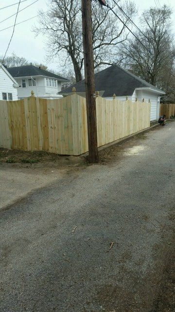 A Wooden Fence Is Along The Side Of A Road Next To A House – Mishawaka IN - Milestone Fence