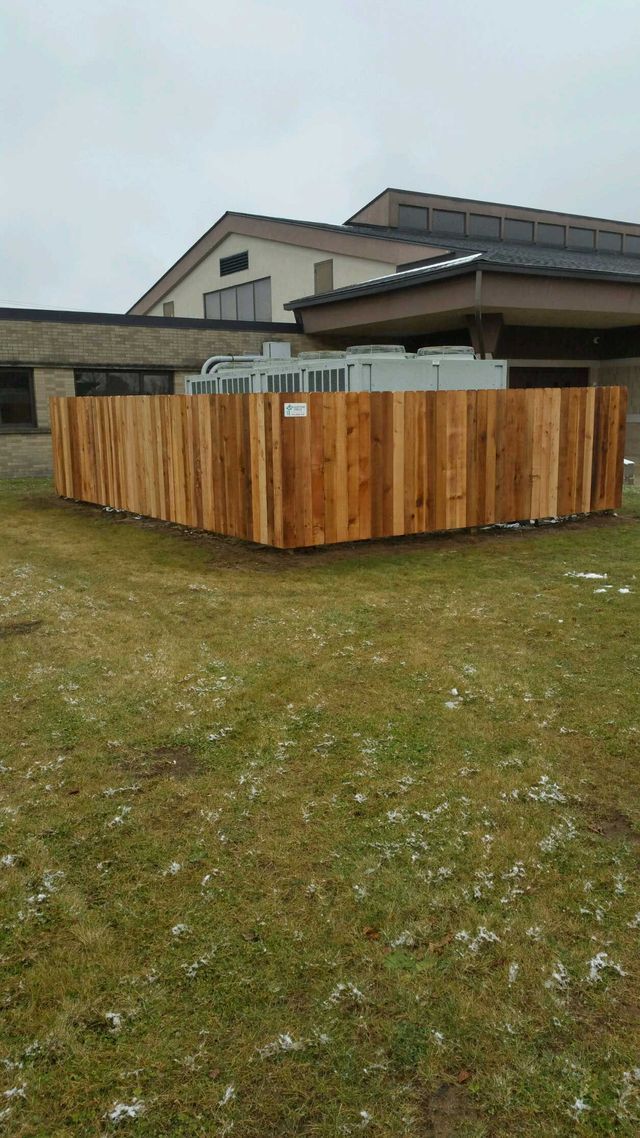 A Wooden Fence Is Sitting In The Grass In Front Of A Building – Mishawaka IN - Milestone Fence