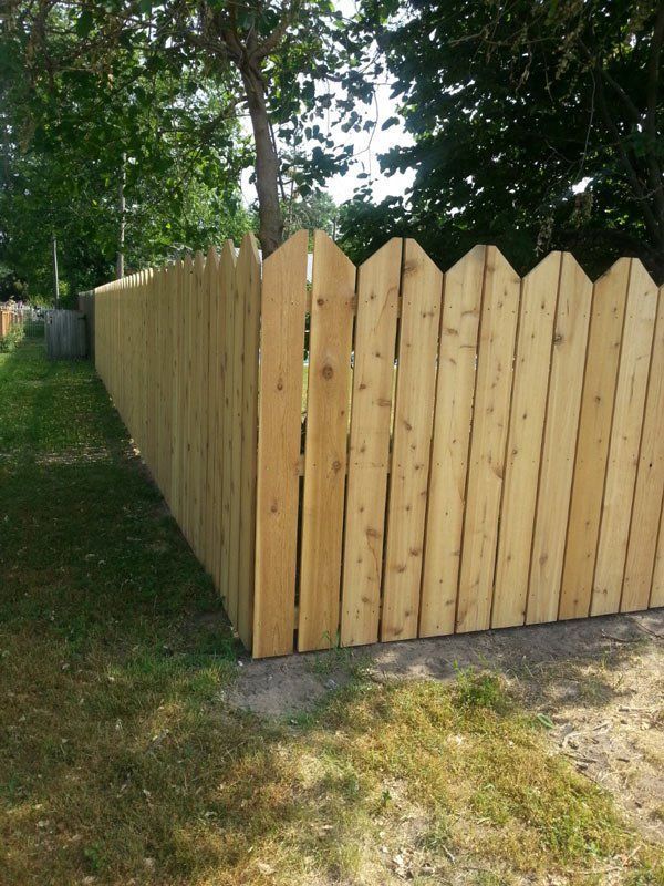 A Wooden Fence Is Surrounded By Grass And Trees – Mishawaka IN - Milestone Fence