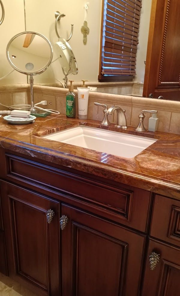 A bathroom with a sink , mirror , and wooden cabinets.