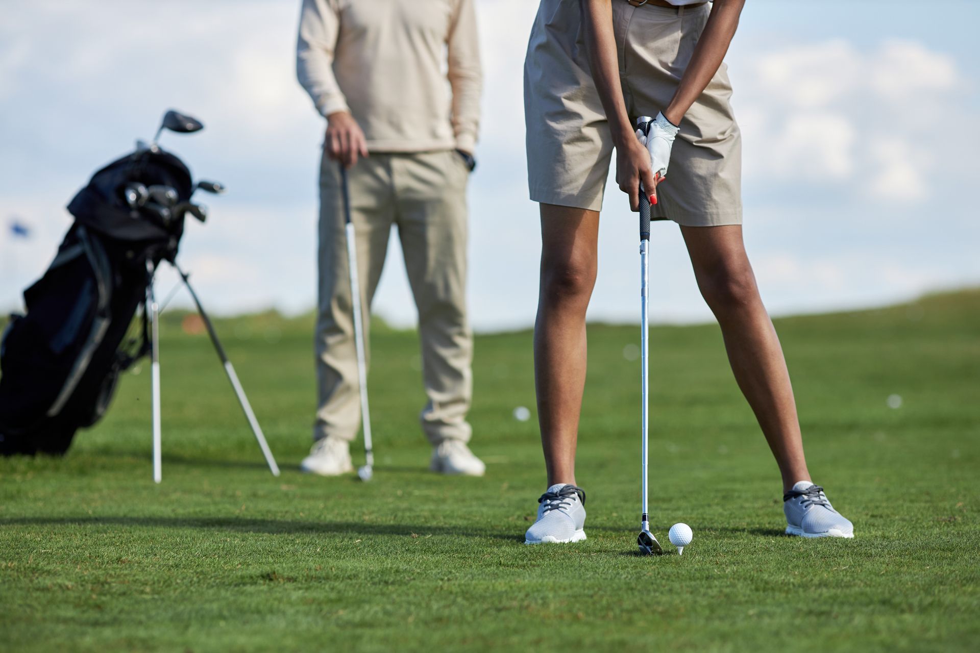 A man and a woman are playing golf on a golf course.