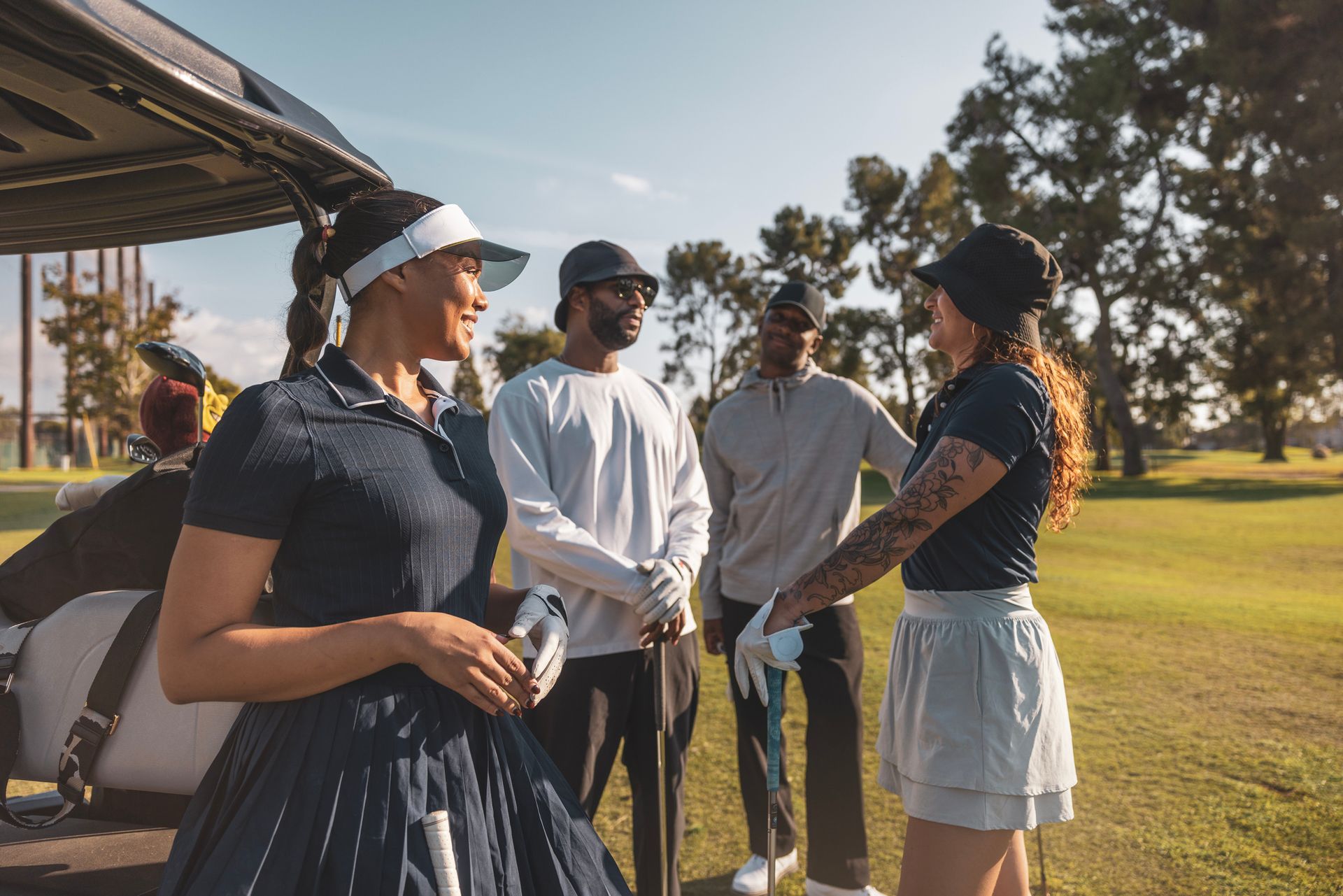 A group of people are standing on a golf course talking to each other.