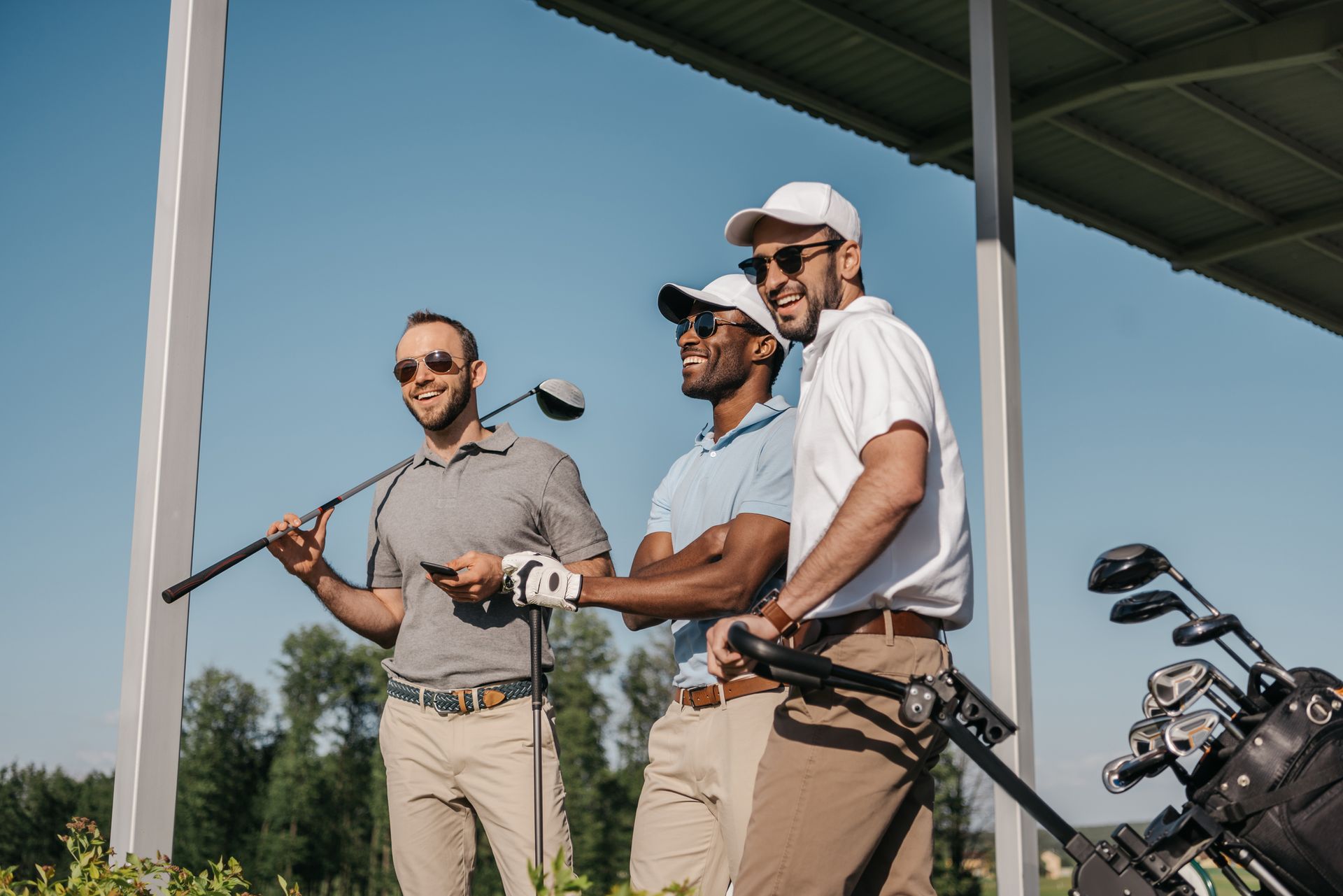 Three men are standing next to each other on a golf course holding golf clubs.