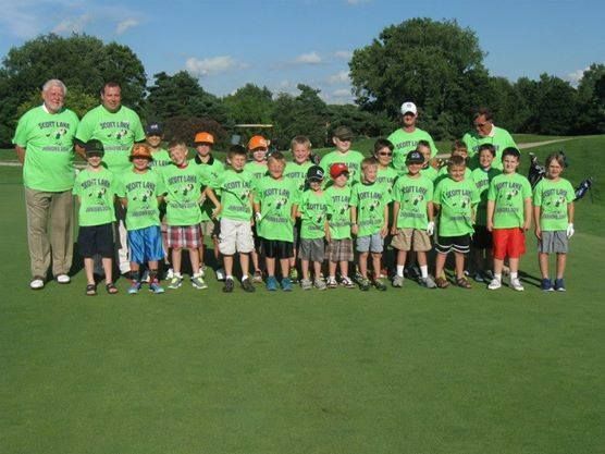 A group of kids wearing green shirts are posing for a picture