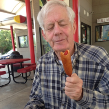A man in a plaid shirt is eating a hot dog