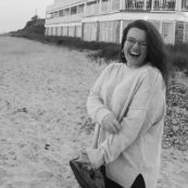A black and white photo of a woman standing on a beach.