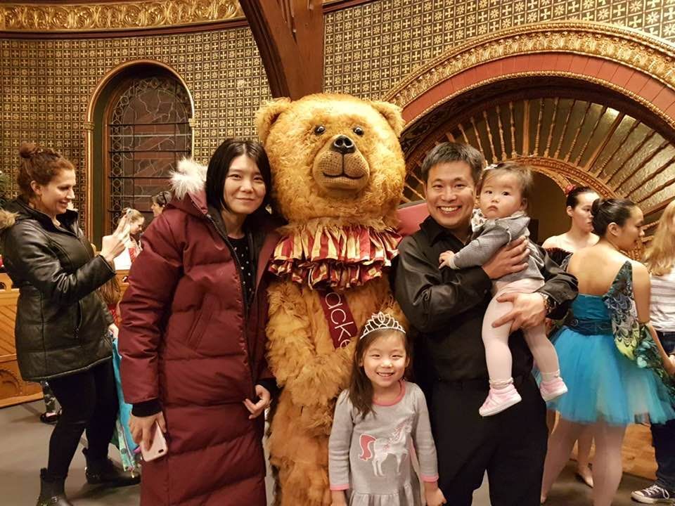 A family posing for a picture with a teddy bear