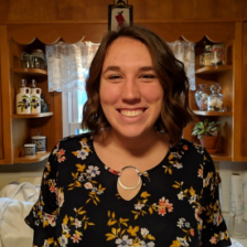 A woman in a floral shirt is smiling in a kitchen