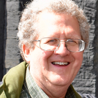 A man wearing glasses and a plaid shirt is smiling for the camera.