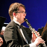 A man in a tuxedo is playing a clarinet in an orchestra