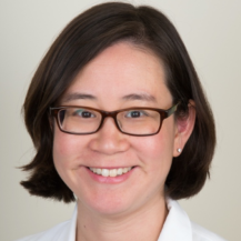 A woman wearing glasses and a white shirt smiles for the camera