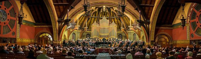 A large group of people are sitting in a church watching a concert.