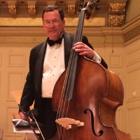 A man in a tuxedo is playing a double bass