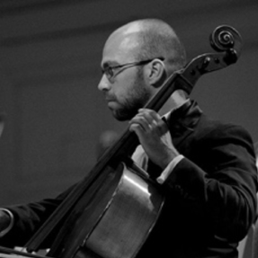 A man in a suit is playing a cello in a black and white photo