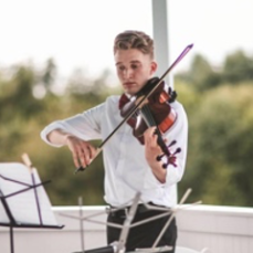 A young man is playing a violin on a balcony.