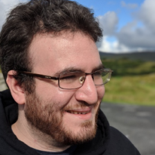 A man with glasses and a beard is smiling