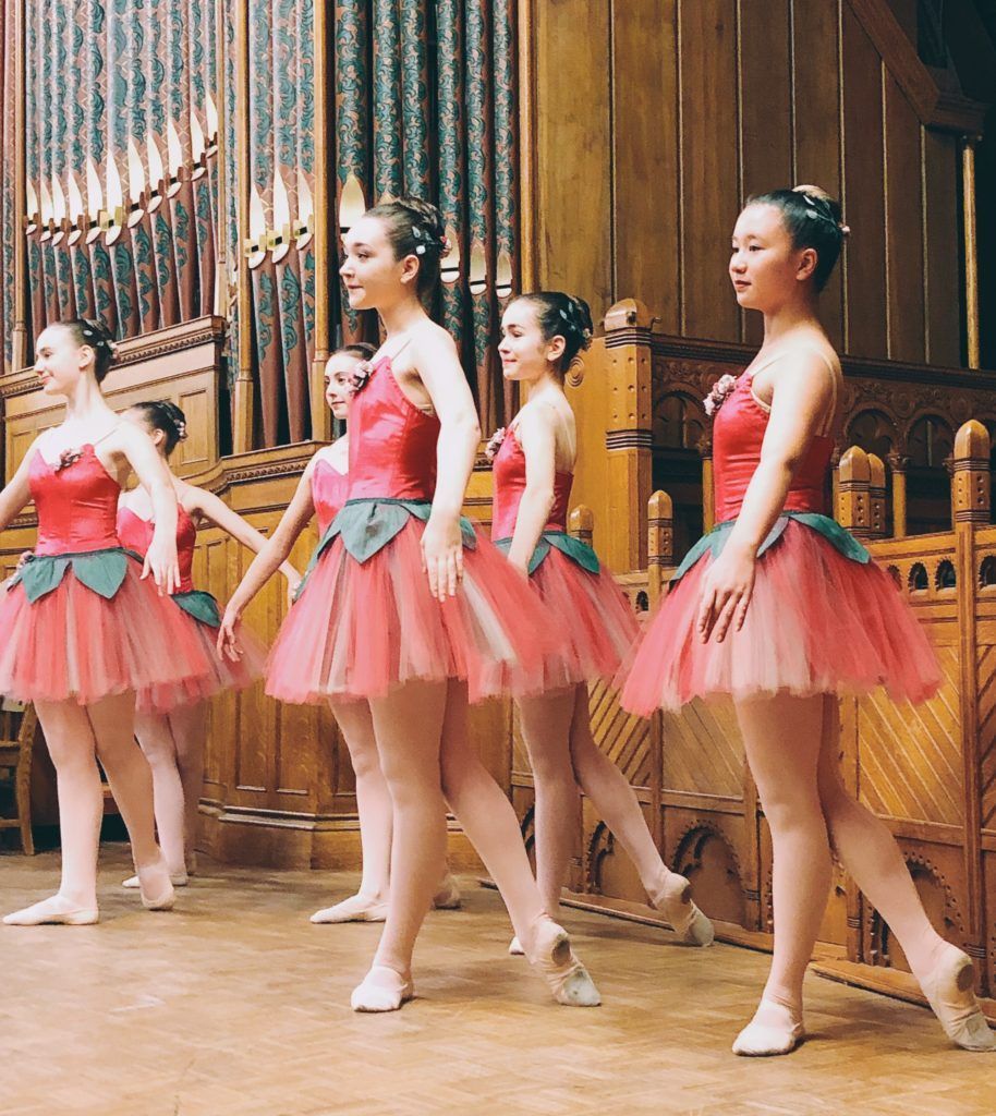 A group of ballerinas are standing in a line on a stage.