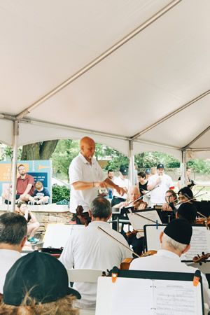 A man is leading an orchestra in a tent.