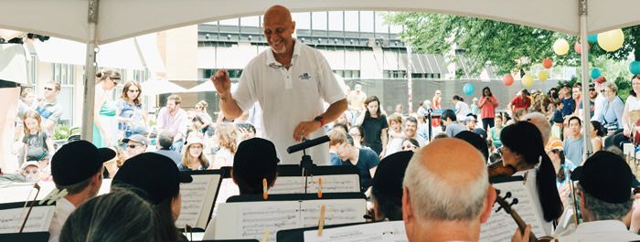 A man is leading an orchestra in front of a crowd.