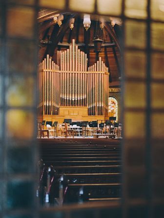 A view of an organ in a church through a window.