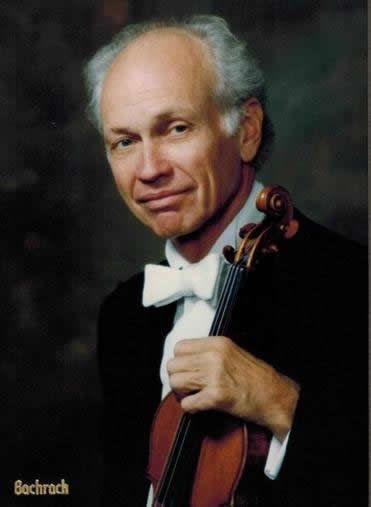 A man in a bow tie is holding a violin