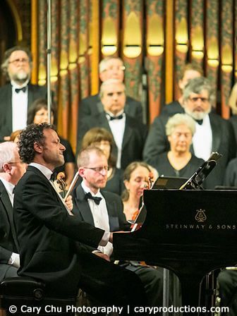 A man is playing a piano in front of a steinway & sons orchestra