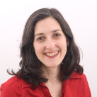 A woman in a red shirt is smiling for the camera.