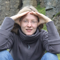 A woman wearing glasses is kneeling down with her hands on her head