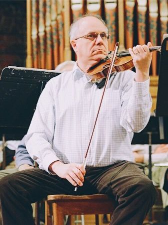 A man is sitting in a chair playing a violin