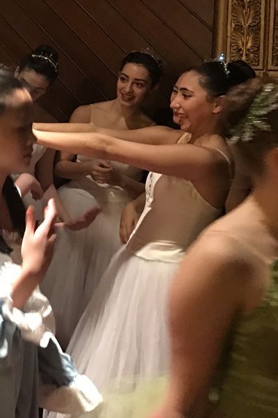 A group of young women in white dresses are standing in a room.