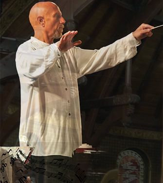 A bald man in a white shirt is standing in front of a piano