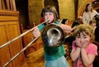 A little girl is playing a trombone in a church.