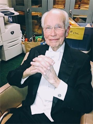 A man in a tuxedo is sitting in front of a printer that says n on it