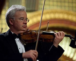 A man in a tuxedo is playing a violin