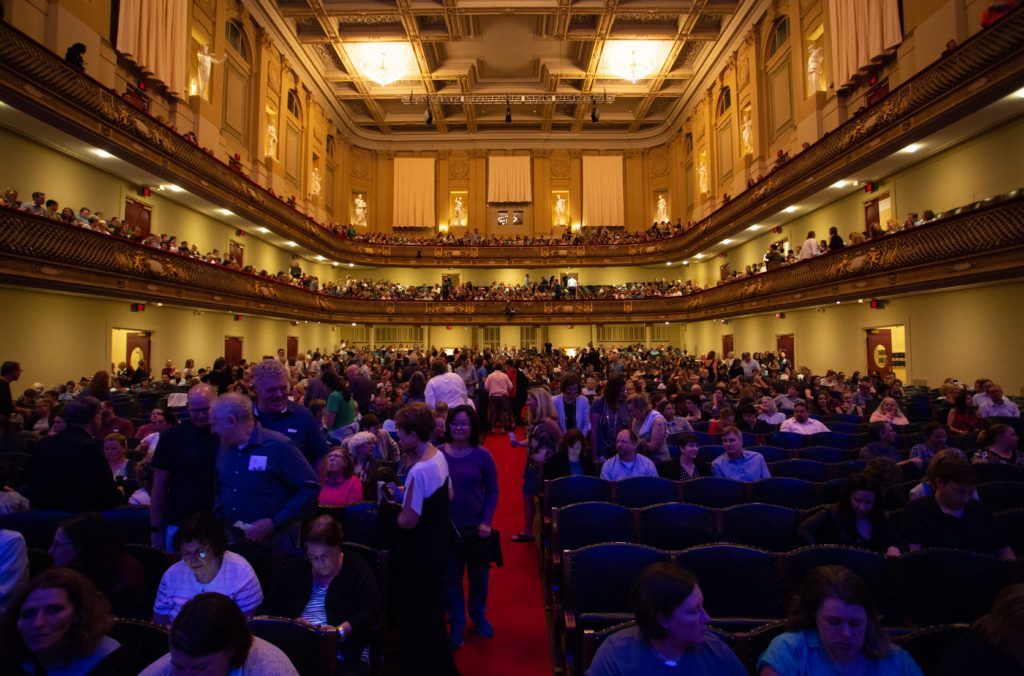 A large auditorium filled with people and a red carpet