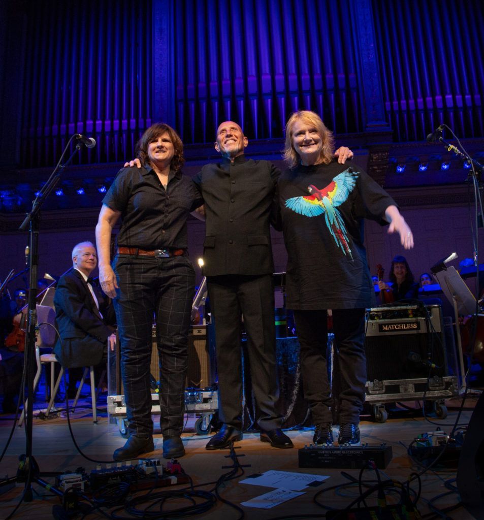 A group of people are standing on a stage with their arms around each other.