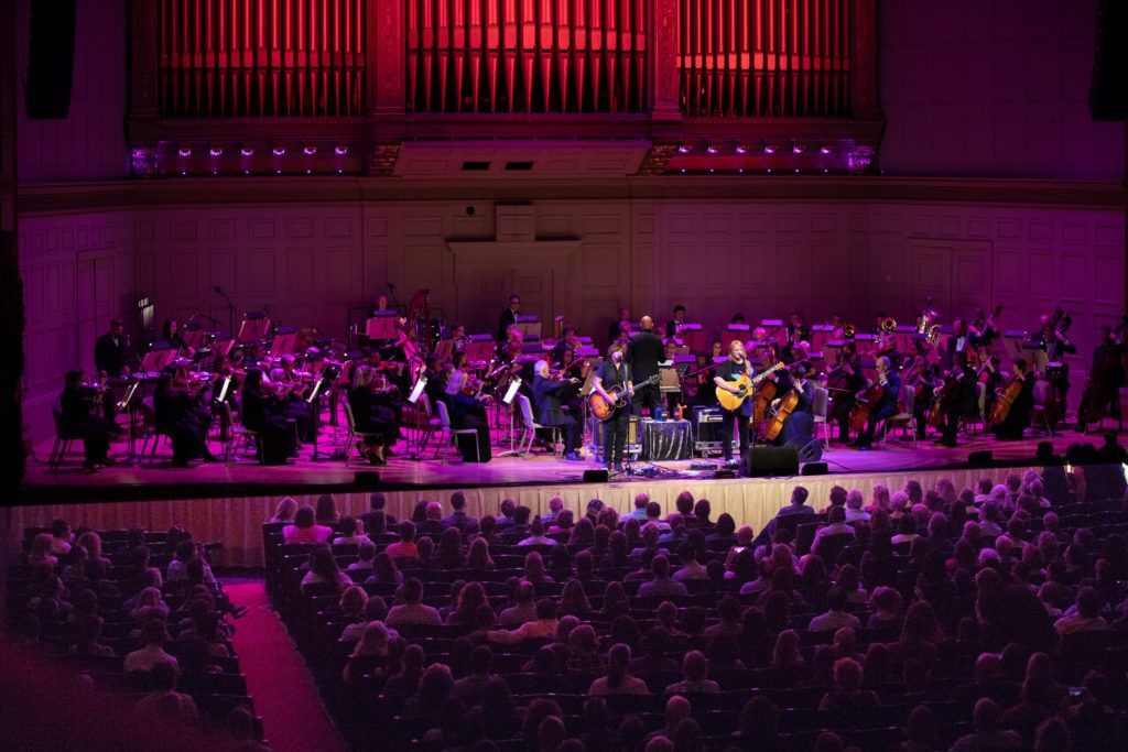 A group of people are playing instruments on a stage in front of a large audience.