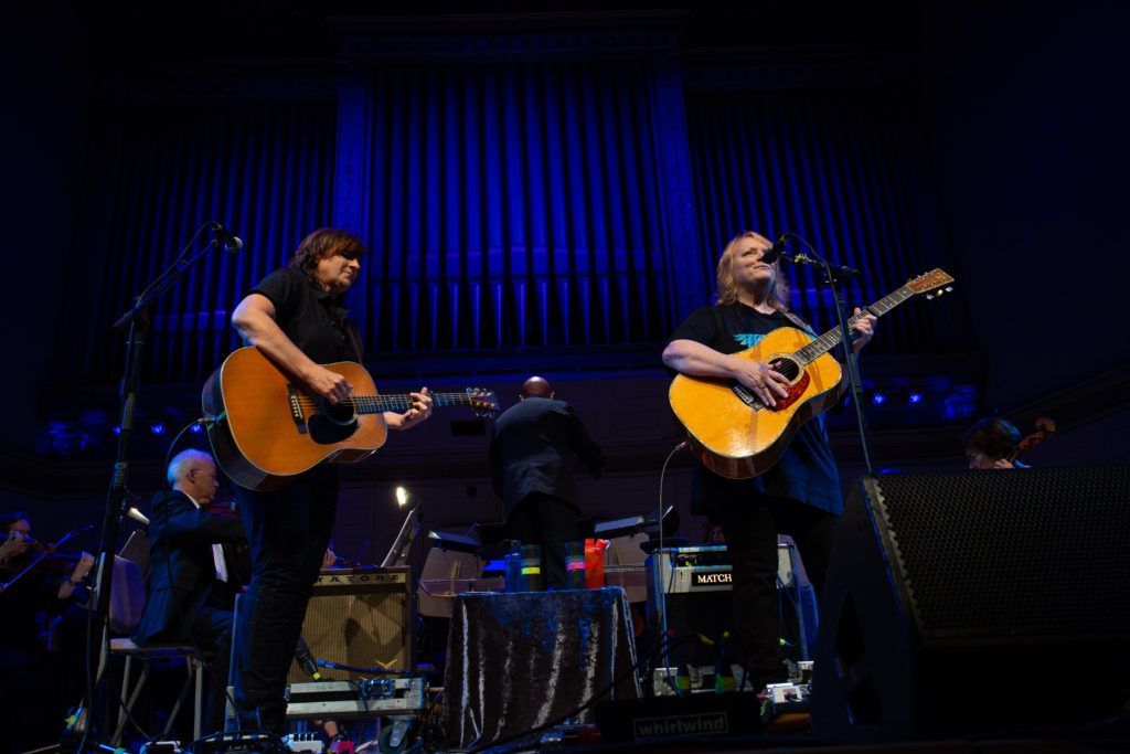Two men are playing guitars on a stage.