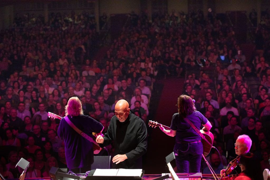 A group of people are playing instruments on a stage in front of a crowd.