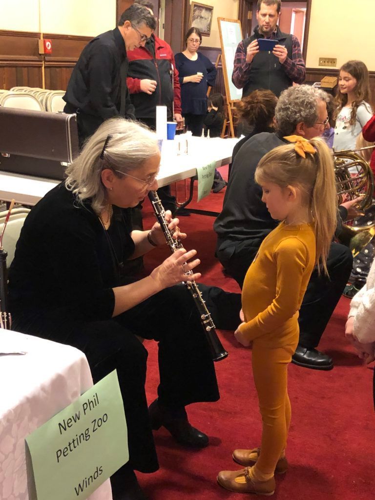A woman is playing a clarinet to a little girl