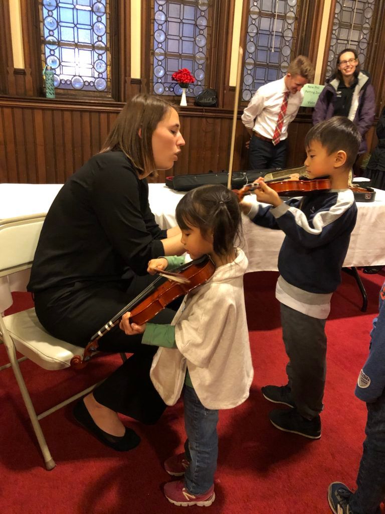 A woman is teaching a child how to play a violin.