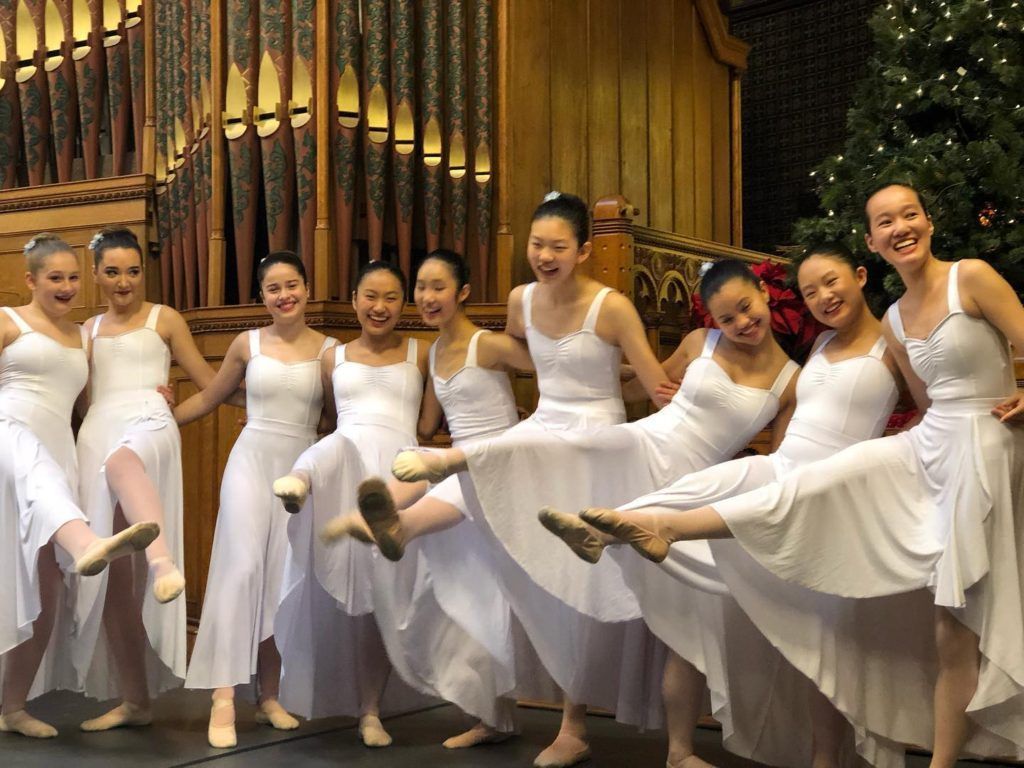 A group of young women in white dresses are posing for a picture.