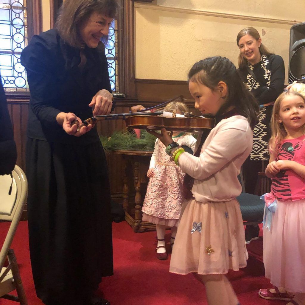 A woman is talking to two little girls in a room.