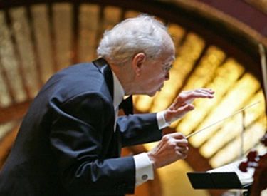 A man in a tuxedo is leading an orchestra